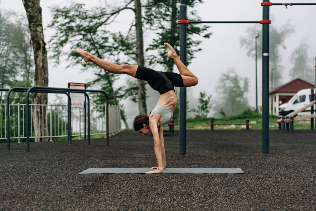 handstand A woman performs a yoga handstand in an outdoor playground, showcasing balance and flexibility.